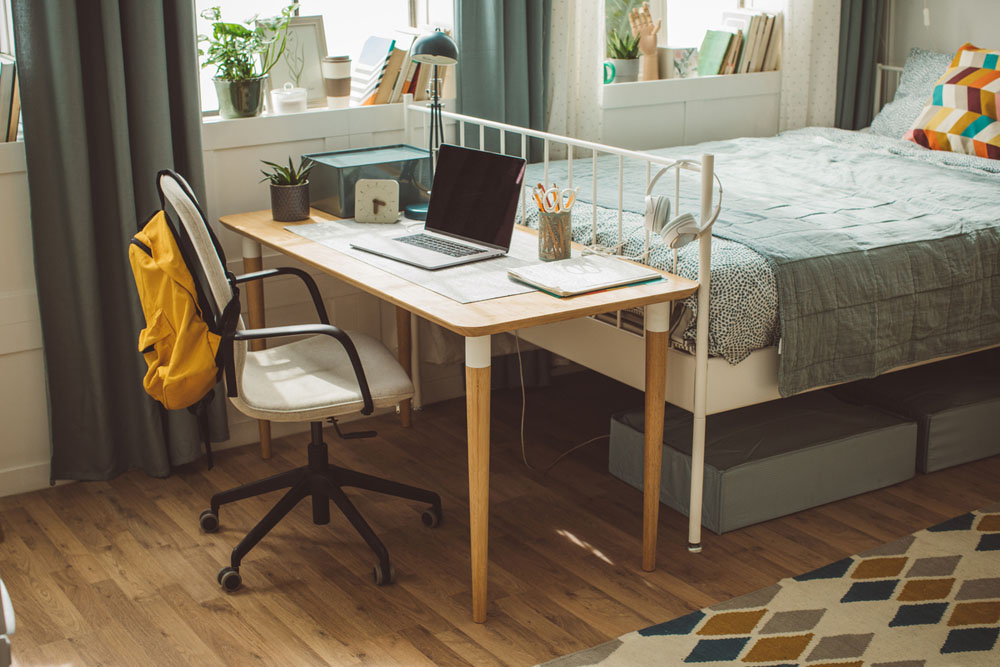 A neatly organized dorm room with a desk, laptop, and study materials