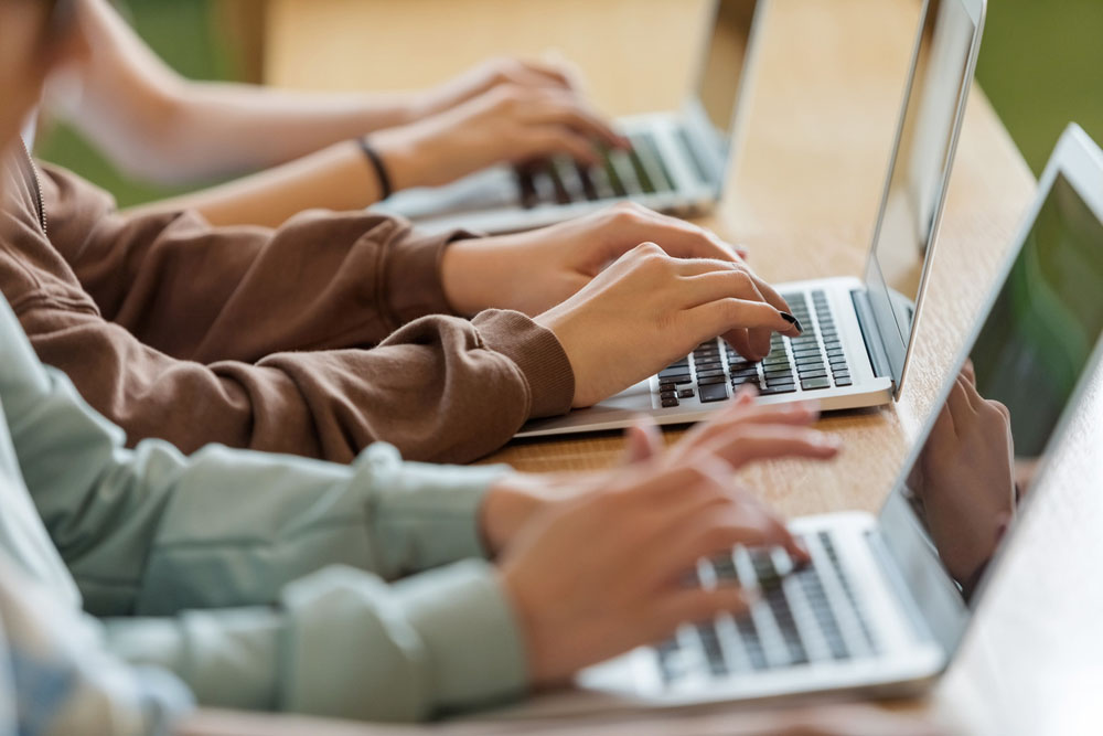Students typing on laptops in a classroom
